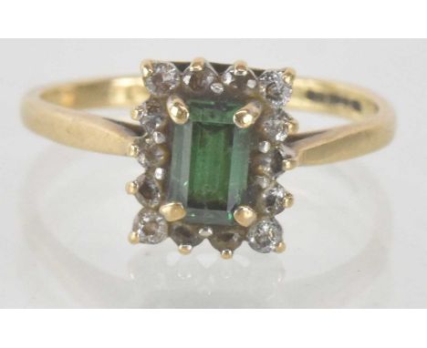 A 9ct yellow gold emerald and white stone set ring, the central rectangular step cut emerald approx 0.4ct, surrounded by mult