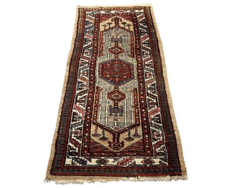 A Persian red and cream ground rectangular carpet with geometric designs, 176 x 91cm.