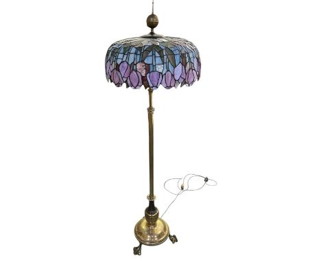 An early 20th century brass standard lamp, with leaded glass Tiffany style shade, on tripod base, height 172cm.