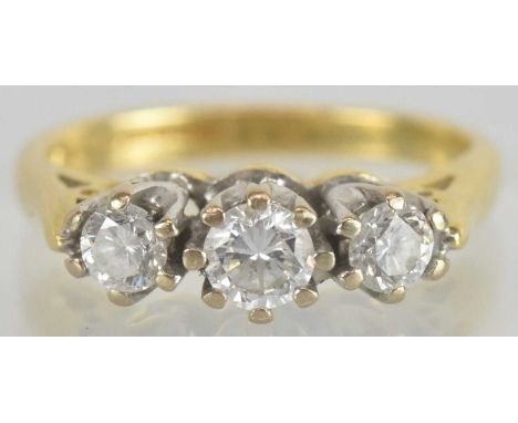 An 18ct yellow gold diamond three stone ring, the central diamond approx 0.2ct, flanked by two smaller round brilliant cut di