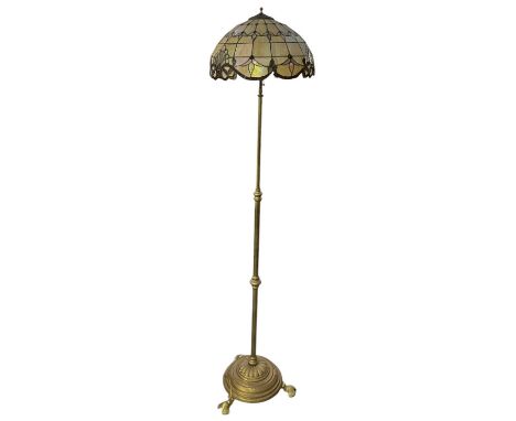 An early 20th century brass standard lamp, with leaded glass Tiffany style shade, on tripod base, height 172cm.