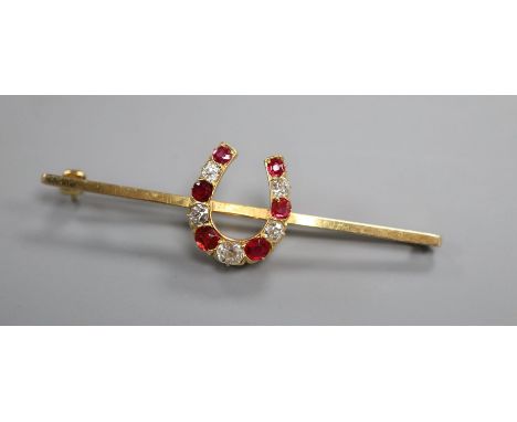 A modern 9ct gold, ruby and diamond set horseshoe bar brooch, 57mm.