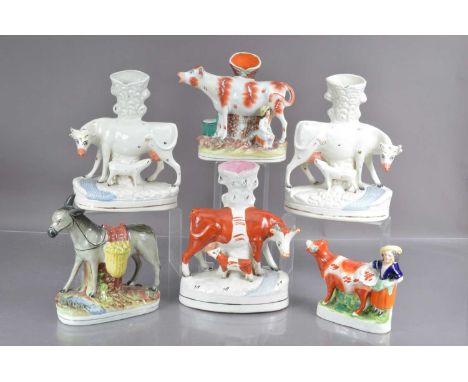 Five Staffordshire flat back cow form spill vases and a donkey, the group including a pair of cows and calves, two further co