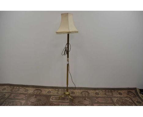 A brass standard lamp with a tripod base, the reeded column with knop to the centre, lions paw feet to base, 160 cm tall incl
