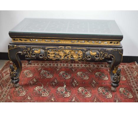 A Chinese style black lacquer and gilt wood coffee table, carved sides and legs, lattice top with glass, on castors, 55 cm hi