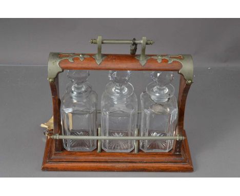 An early 20th century oak and silver plated (now dulled) cut glass Tantalus, together with a Georgian silver Brandy label mar