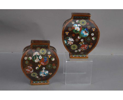 An unusual pair of Japanese Meiji period cloisonné moon flasks, of bombé form the sides decorated with various flowers and sy