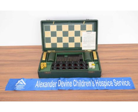 An early 20th century games compendium, the green vinyl covered hinged box, fitted with a draft board and counters, die shake