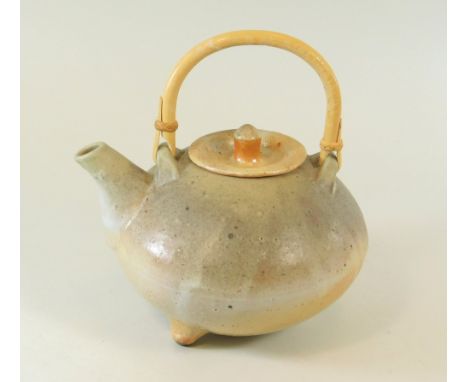 SVEND BAYER. SHEEPWASH POTTERY. A cane handled teapot on tripod feet. Width 18cm.