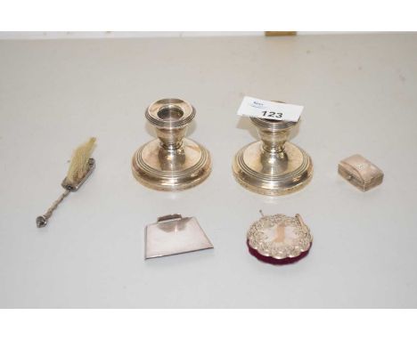 A pair of small silver mounted loaded dressing table candlesticks, a miniature dustpan and brush, pin cushion and a pill box 