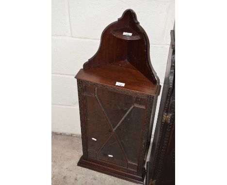 An Edwardian mahogany wall mounted corner cabinet with pierced pediment