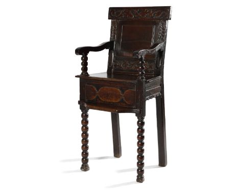 A WILLIAM AND MARY OAK CHILD'S HIGHCHAIR C.1690 the panelled back carved with scrolling tulips and leaves, the scroll arms on