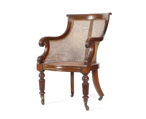A WILLIAM IV MAHOGANY BERGERE C.1835-40 with a curved scroll top rail above a caned back and seat, with lappet carved arms on