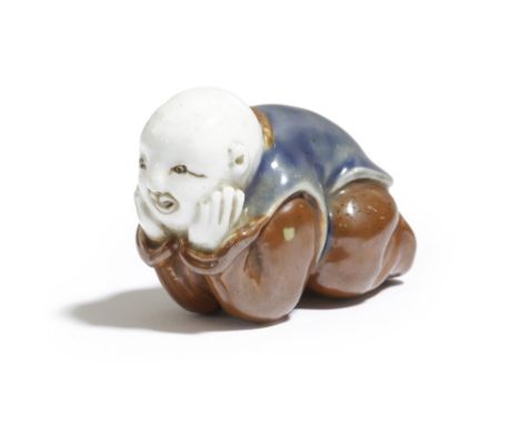 A JAPANESE HIRADO PORCELAIN NETSUKE OF A KARAKO LATE EDO / MEIJI PERIOD, 19TH CENTURY the Chinese boy lying on his belly and 