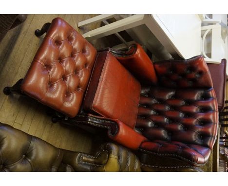 A Vintage red Chesterfield wingback armchair and matching footstool.