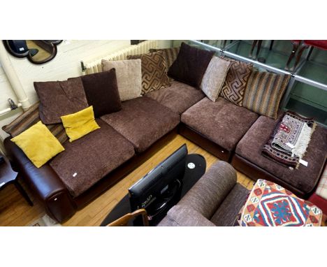 A modern brown leather and material corner sofa, with assorted cushions.