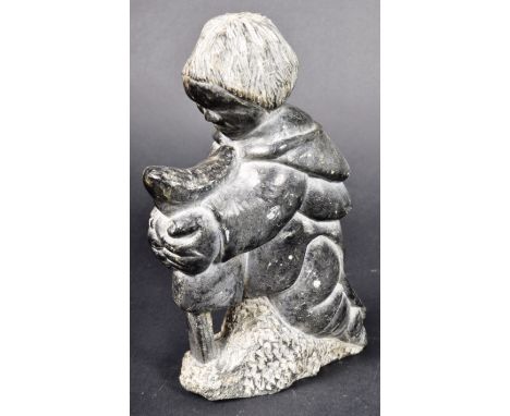 Davidee Saumik - A large Inuit art hand carved polished shiny black stone figurine depicting a male figure skinning a seal. T