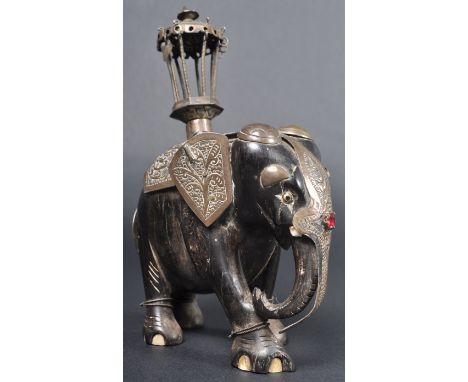 A 19th Century Indian Hindu Ebony wood &amp; brass carved elephant figure. The Elephant depicted with its trunk lowered &amp;