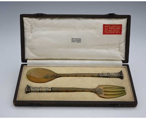 Omar Ramsden.A George V Arts & Crafts silver-gilt-mounted cased serving fork and spoon set, crafted from horn, the stem of ea