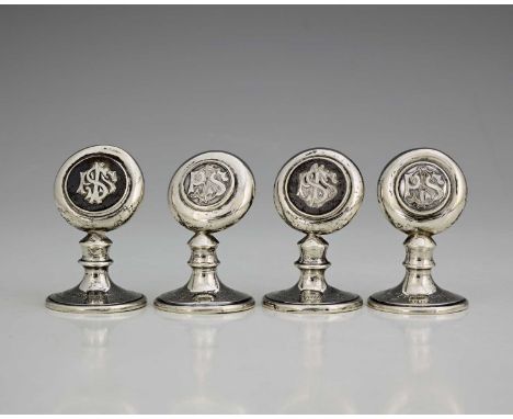 A matched set of four Edwardian silver and enamel menu or place card holders, each atop a flared foot, applied with an enamel
