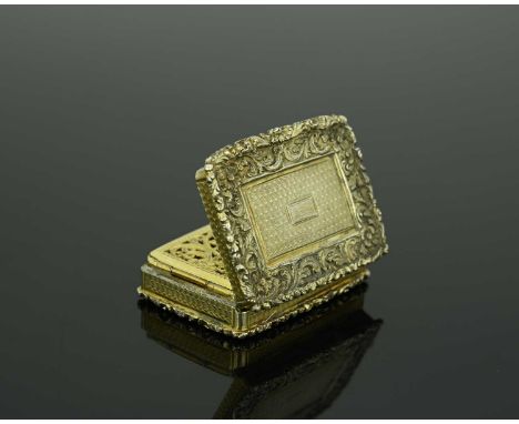 A William IV silver-gilt vinaigrette, of rectangular form, with cast foliate scroll border, the underside decorated with engi