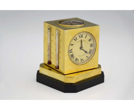An early twentieth-century silver-gilt metal desk compendium, of cube form, atop a stepped revolving base, comprising compass