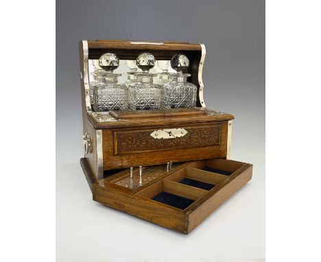 A George V silver-mounted carved oak gentleman's compendium, comprising three-bottle cut-glass tantalus, the central section 