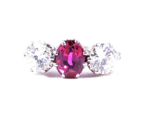A ruby and diamond three stone ring, an oval mixed cut ruby, 7.8x5.6x4.4mm, with one modern brilliant cut diamond to each sid