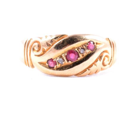 An 18 carat yellow gold ring set with three small rubies, the stones set at an angle and spaced by two small rose cut diamond