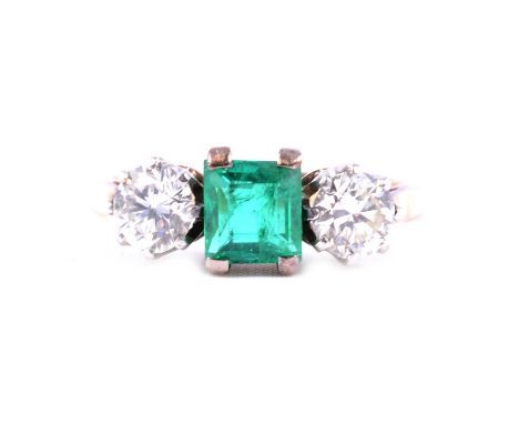 A synthetic emerald and diamond three stone ring, the step cut emerald 5.6x5.4mm, four claw set with a 4.8mm brilliant cut di