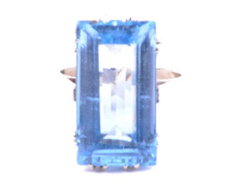 A synthetic blue spinel dress ring, the rectangular step cut stone, 22x12mm, set with double claws in an all white metal moun