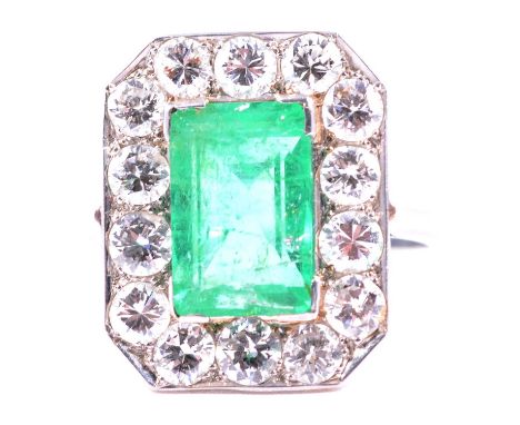 An emerald and diamond rectangular cluster ring, the rectangular step cut emerald 11x7mm, set with corner claws and surrounde