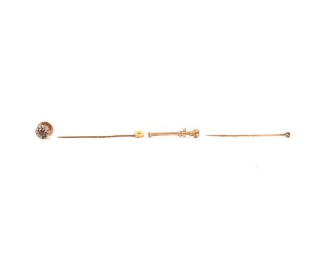 A pink stone and diamond stick pin, a small diamond set tie pin and a yellow metal toothpick, a pink stone and diamond stick 