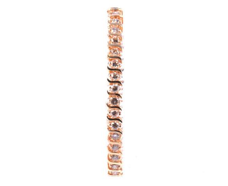 A diamond tennis bracelet, the thirty-five brilliant cut stones claw set and divided by yellow metal S shape links, tongue sn