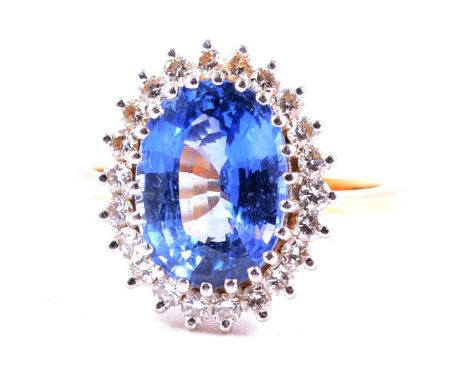 A Sri Lankan sapphire and diamond cluster ring, the oval mixed cut medium to light blue sapphire, 11.5x8.5mm, claw set and su