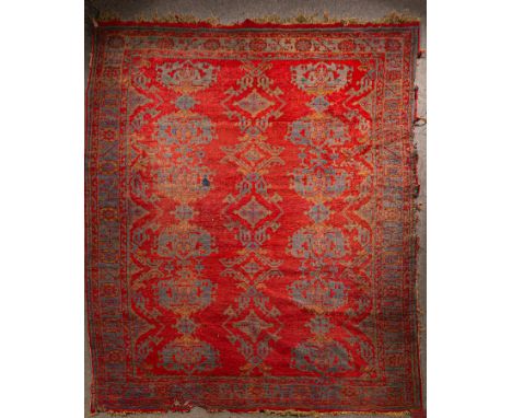 An Ushak carpet, West Anatolia, circa 1910, the tomato red field with three rows of palmettes and lozenges, framed by a steel