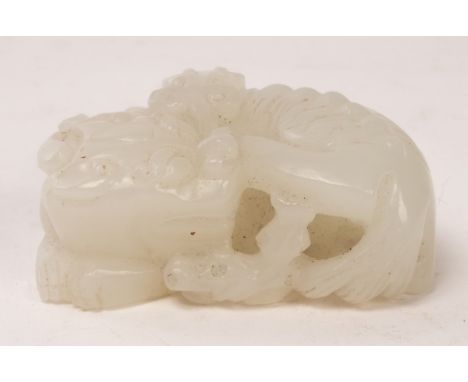 A Chinese white jade carved beast Pixiu, 19th/20th Century, the recumbent animals head turning backwards and biting the stem 