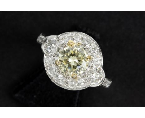a 0,91 carat high quality fancy yellow brilliant cut diamond set in a ring in white gold (18 carat) with ca 1 carat of very h