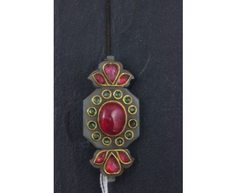 A jade bar brooch; of Indian design; set with rough cut rubies and green glass stones; the verso incised with floral decorati