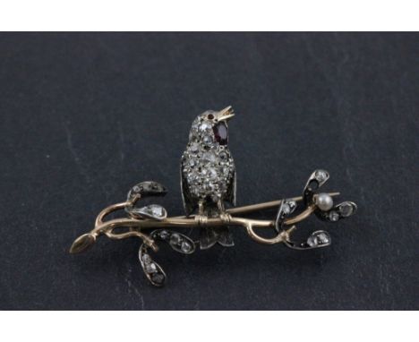 A diamond and ruby bar brooch mounted in gold; in the form of a robin on a branch of mistletoe