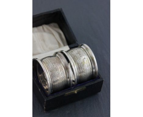 A cased pair of hallmarked napkin rings; William Aitken: Birmingham 1899; with engine turned decoration
