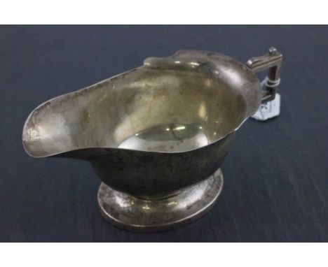 A Edwardian hallmarked silver helmet form sauceboat; with stylised 'C' scroll handle; Cooper Brothers; Sheffield 1936