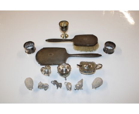 A box containing two silver napkin rings, silver egg cup, three silver cruet items, silver backed dressing table hand mirror 