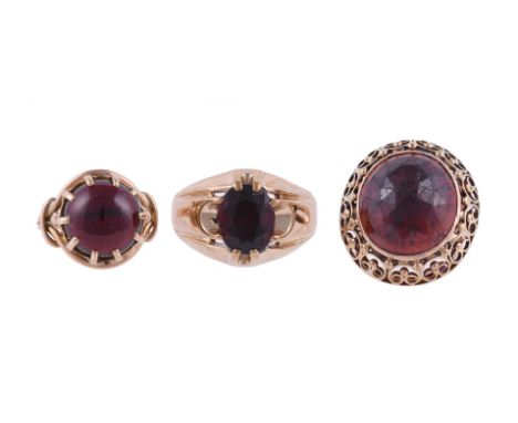 
	
		THREE GARNET DRESS RINGS
		The first with a rose cut garnet within a two colour scrolled and beaded setting; the second 