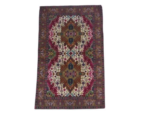 A Tabriz rug, with two rust coloured medallions to central panel, on cream and burgundy ground, densely decorated with geomet
