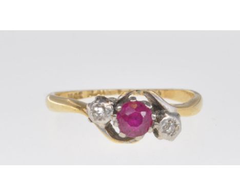 A stamped 18ct gold three stone ring set with a central round cut ruby flanked by two round cut diamonds in platinum settings