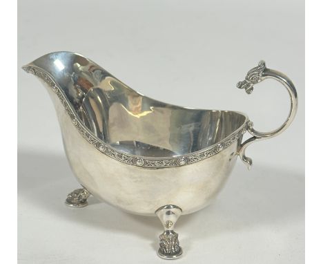 A Sheffield silver Celtic style sauce boat, with chased S scroll dragon mask handle and shield a Celtic knot panel border to 