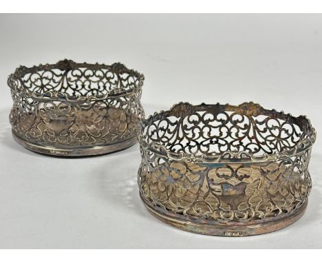 A pair of Edwardian Epns pierced wine slides with scrolling panel sides and oak turned felt bases, (H x 7.5cm x D 14cm) (2)