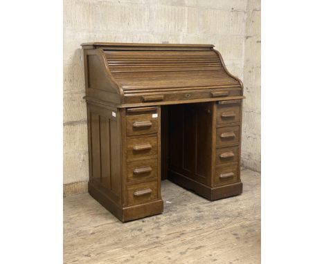 An Edwardian oak roll top desk, the serpentine tambour front with key and lock escutcheon stamped The Lebus Desk, opening to 