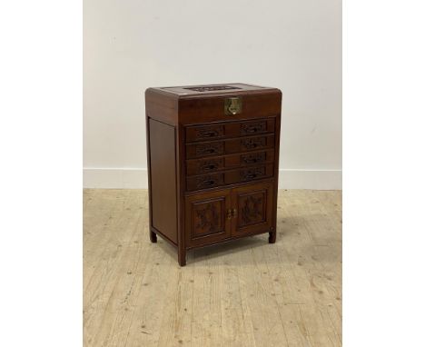 A Chinese style hardwood canteen cabinet, the carved panel top opening to a fitted interior, above four drawers with fitted i